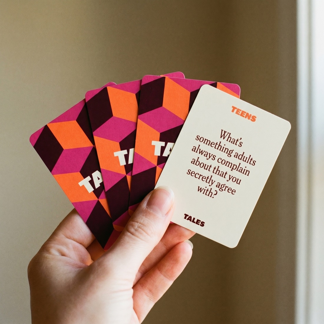 A hand holding a fan of Tales Teens cards showing the colorful card backs